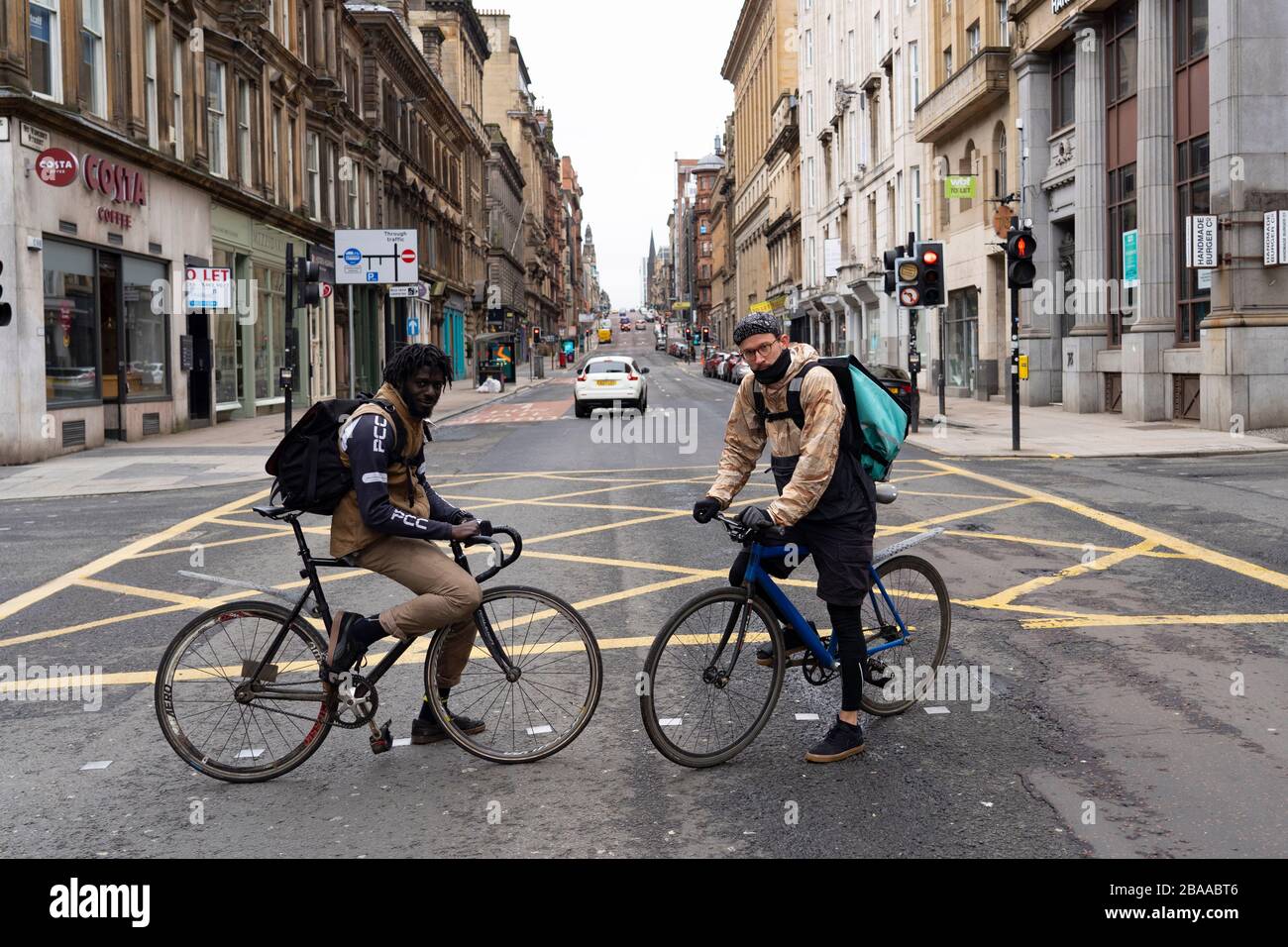 Glasgow, Scotland, UK. 26 March, 2020. Views from city centre in Glasgow on Thursday during the third day of the Government sanctioned Covid-19 lockdown. The city is largely deserted. Only food and convenience stores open. Pictured; Two Deliveroo delivery cyclists pause for a portrait .Iain Masterton/Alamy Live News Stock Photo