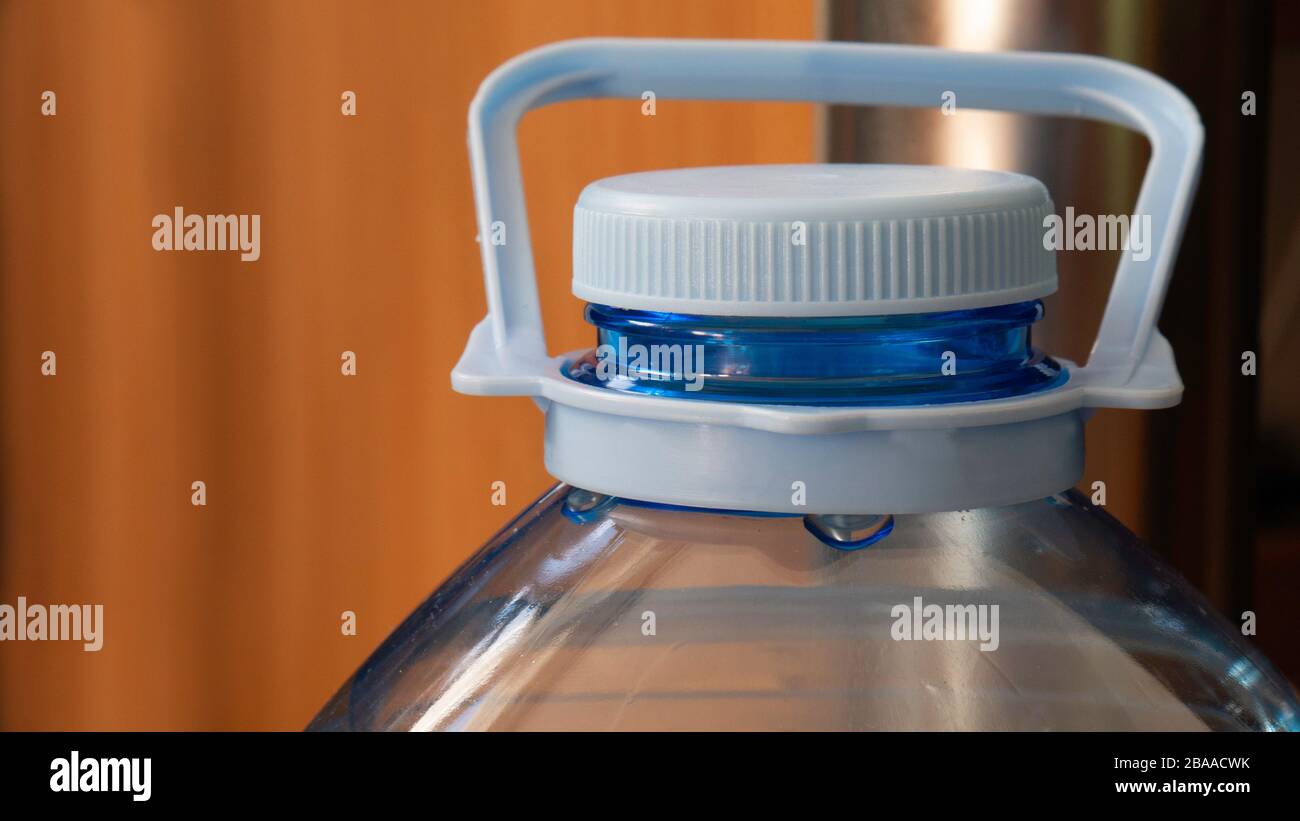Five liter bottle - close up. Plastic container with water. Blue plastic bottle stopper. Stock Photo