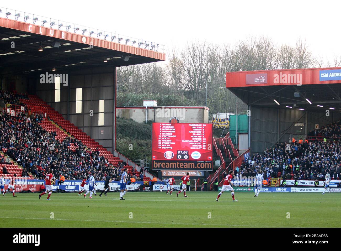 The giant screen shows the team sheet as the action takes place on the pitch Stock Photo