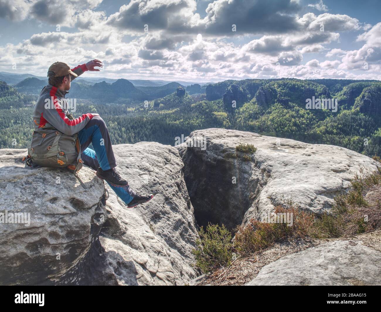 Male hiker meditating on flat place above valley. Amazing view into pure nature. Sunny spring day Stock Photo
