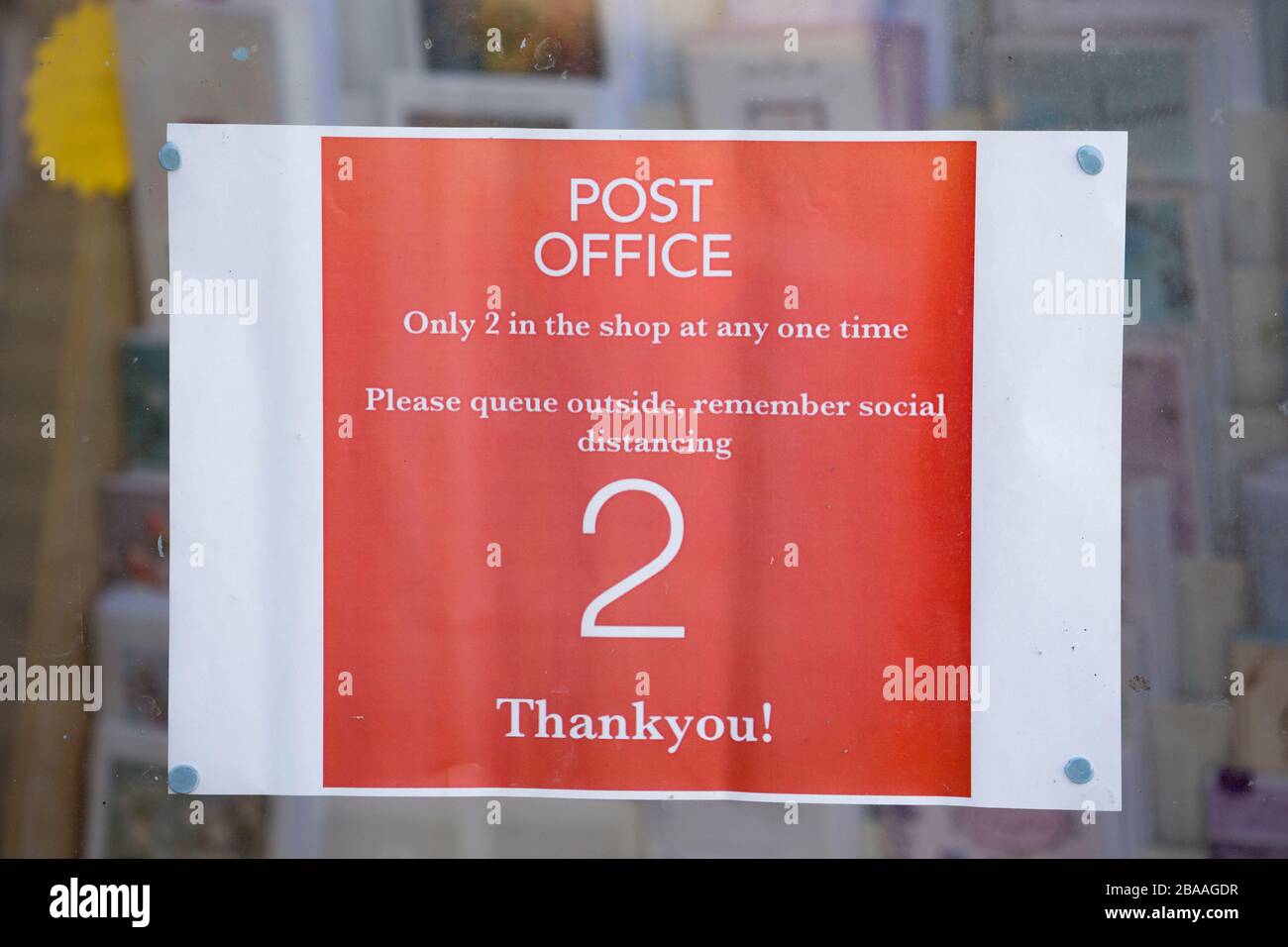 A sign in the window of a Post Office in Gillingham, Dorset indicating that only two people at a time are allowed in due to the outbreak of the Corona Stock Photo