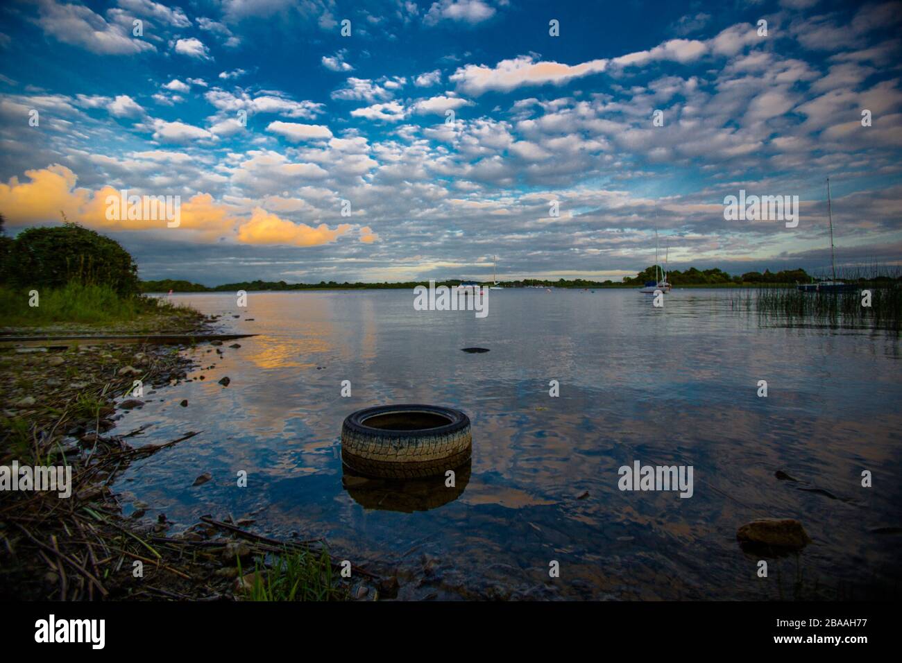 A rubber car tire sits in Lake Red, County Westmeath, Isolation as a symbol in Ireland. Stock Photo