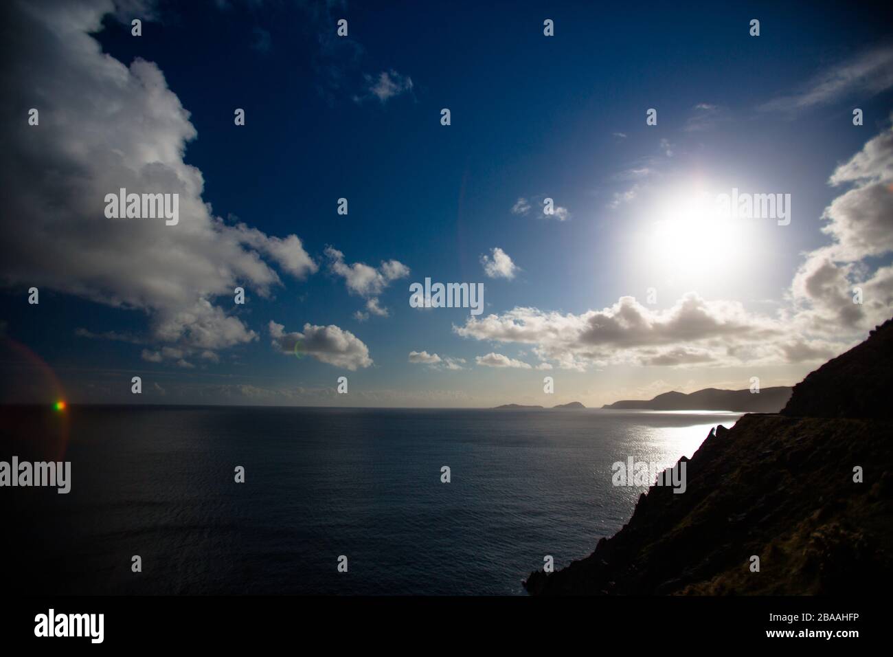 The sun sets on a blue sky day on the coastal view an island and Irish coast, Ireland Stock Photo