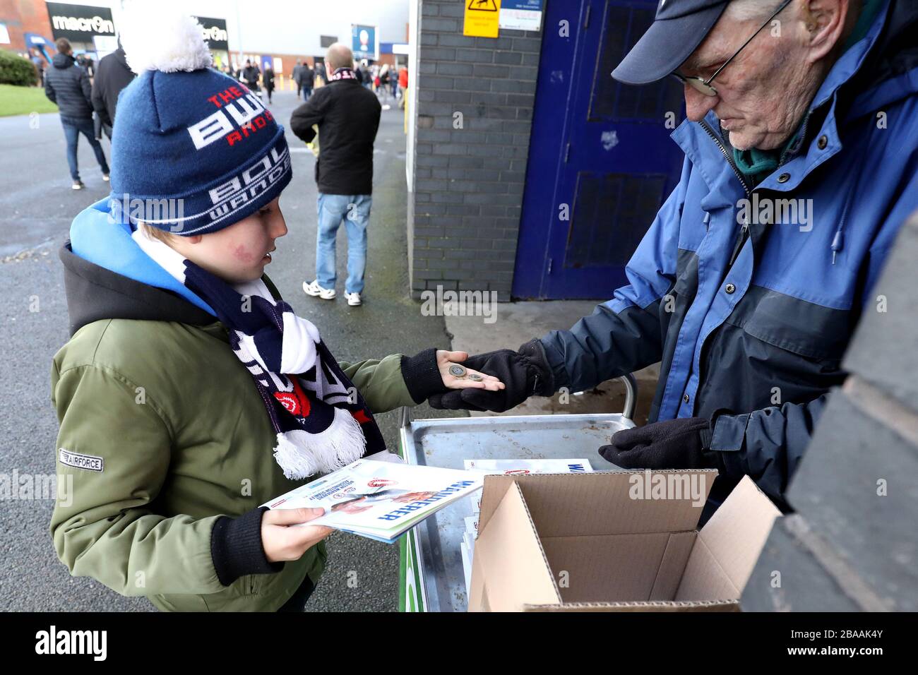 A young Bolton Wanderers fan buys a programme prior to the match Stock Photo