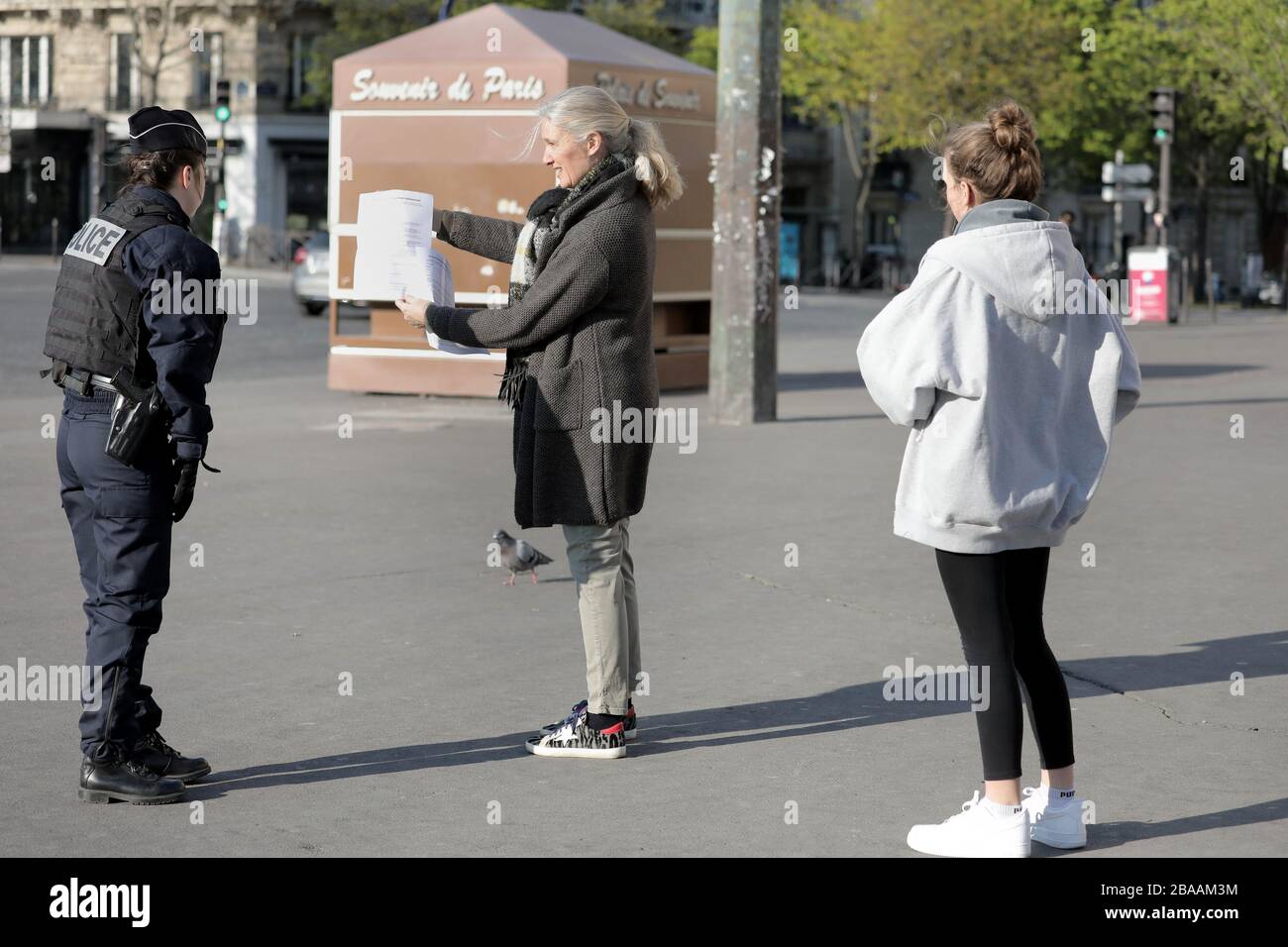 Paris, France. 26th Mar, 2020. Security forces keep their distances to protect themselves from a potential infection as they check residents for the documents allowing them to be in the streets of Paris, France, Thursday, March 26, 2020. French authorities tightened lockdown rules on physical exercise today limiting outings to one hour maximum as the coronavirus epidemic continues to spread in the country with 1,331 dead, including 186 in past 24 hours. Photo by Eco Clement/UPI Credit: UPI/Alamy Live News Stock Photo