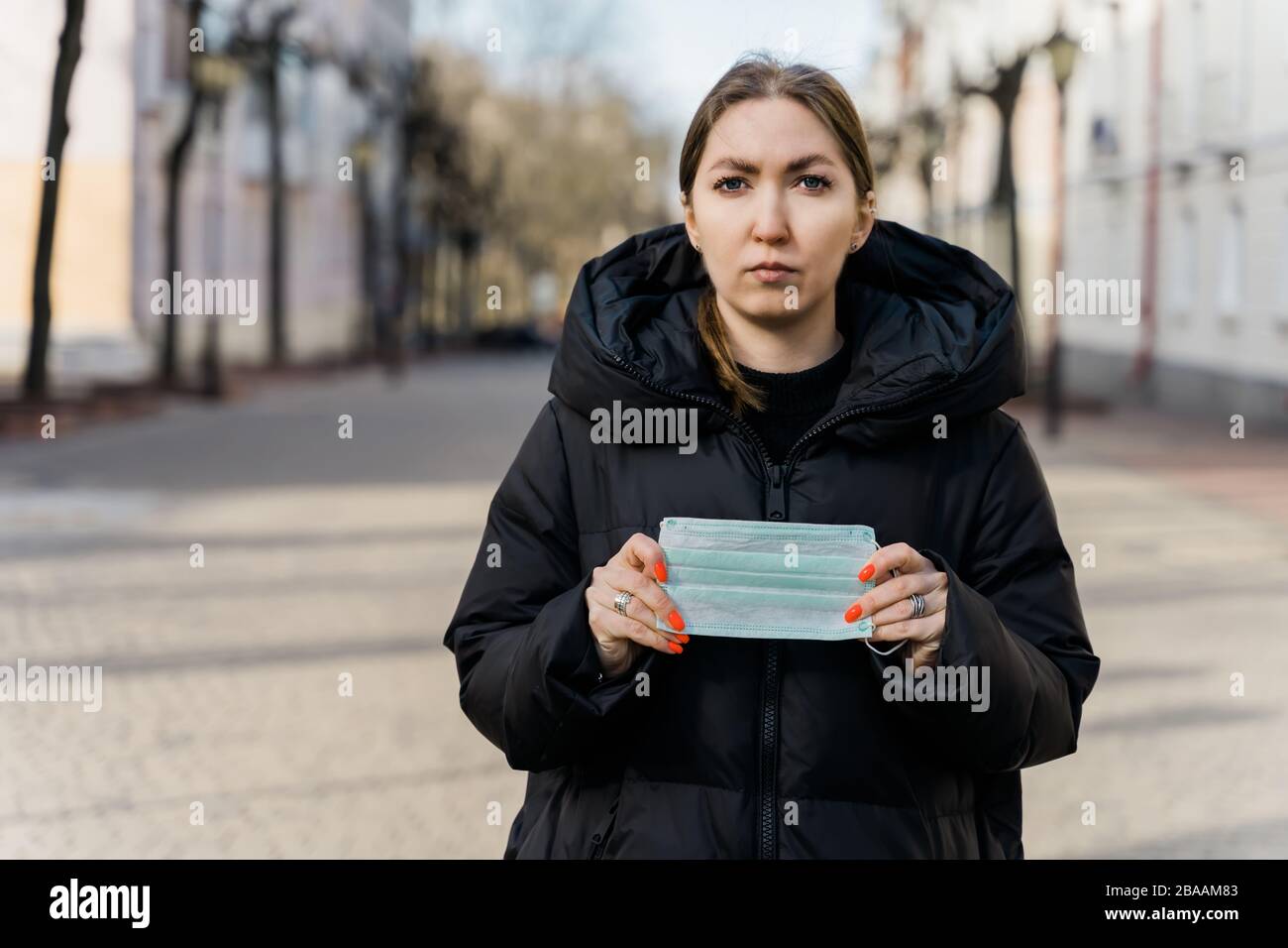 Portrait of a young tourist woman wearing protective mask on empty european streets. Pandemic Covid-19 coronavirus protection. Stock Photo