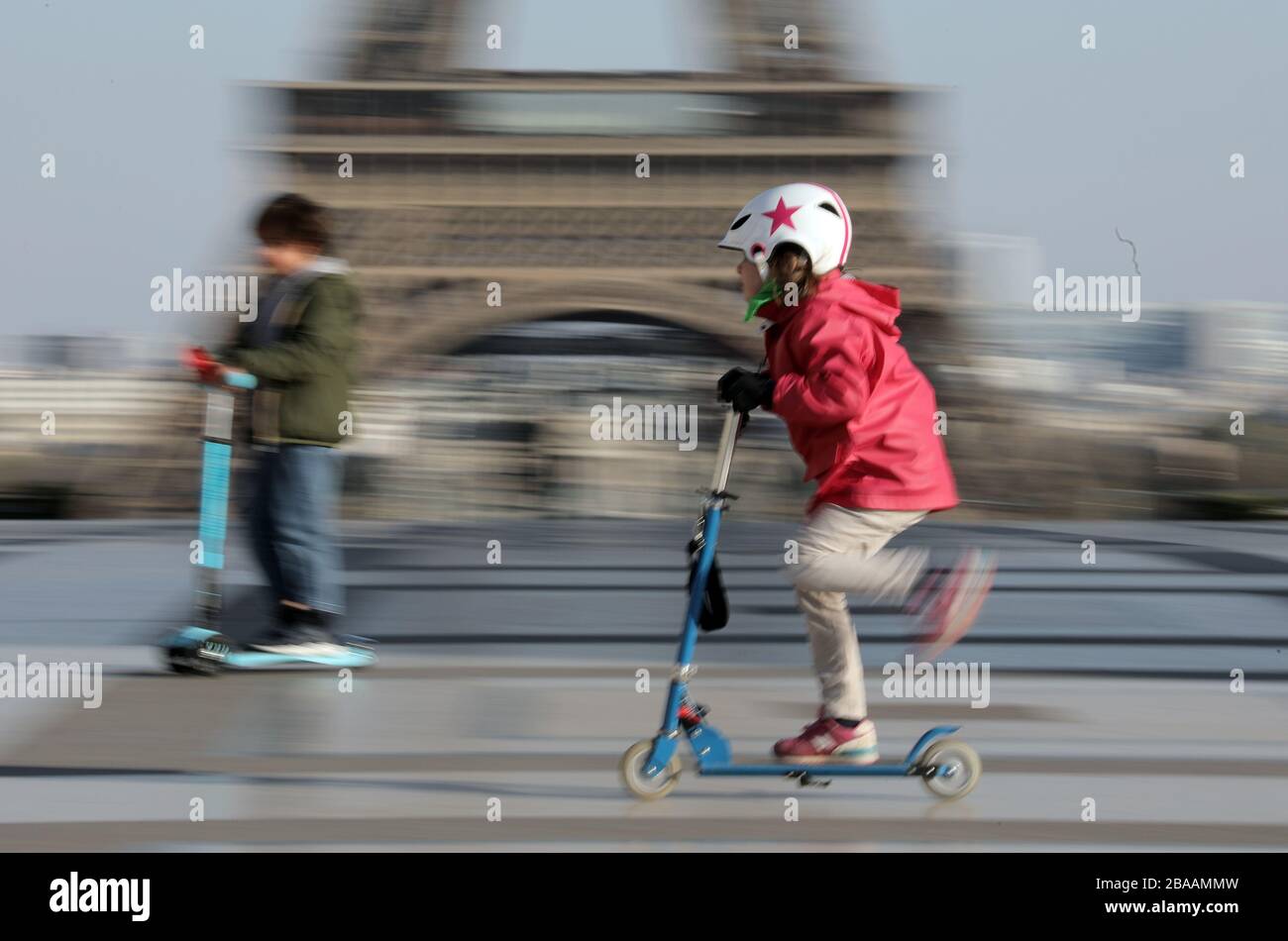 Paris, France. 26th Mar, 2020. Children ride their scooters in front of the Eiffel Tower in Paris, France on Thursday, March 26, 2020. French authorities tightened lockdown rules on physical exercise today limiting outings to one hour maximum as the coronavirus epidemic continues to spread in the country with 1,331 dead, including 186 in past 24 hours. Photo by Eco Clement/UPI Credit: UPI/Alamy Live News Stock Photo
