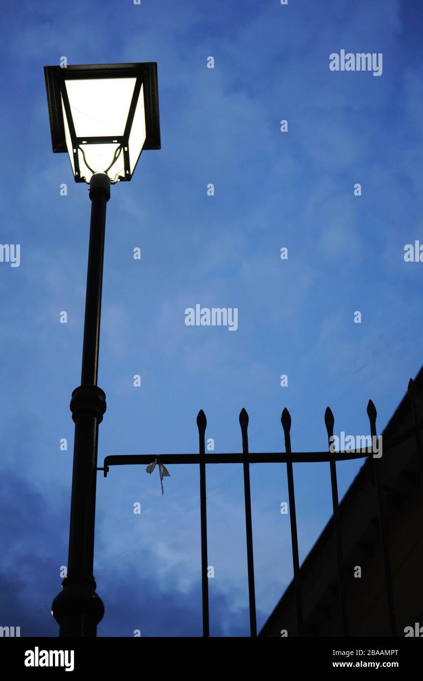 silhouette of Spanish streetlight next to metal bars in night time on a cloudy day Stock Photo