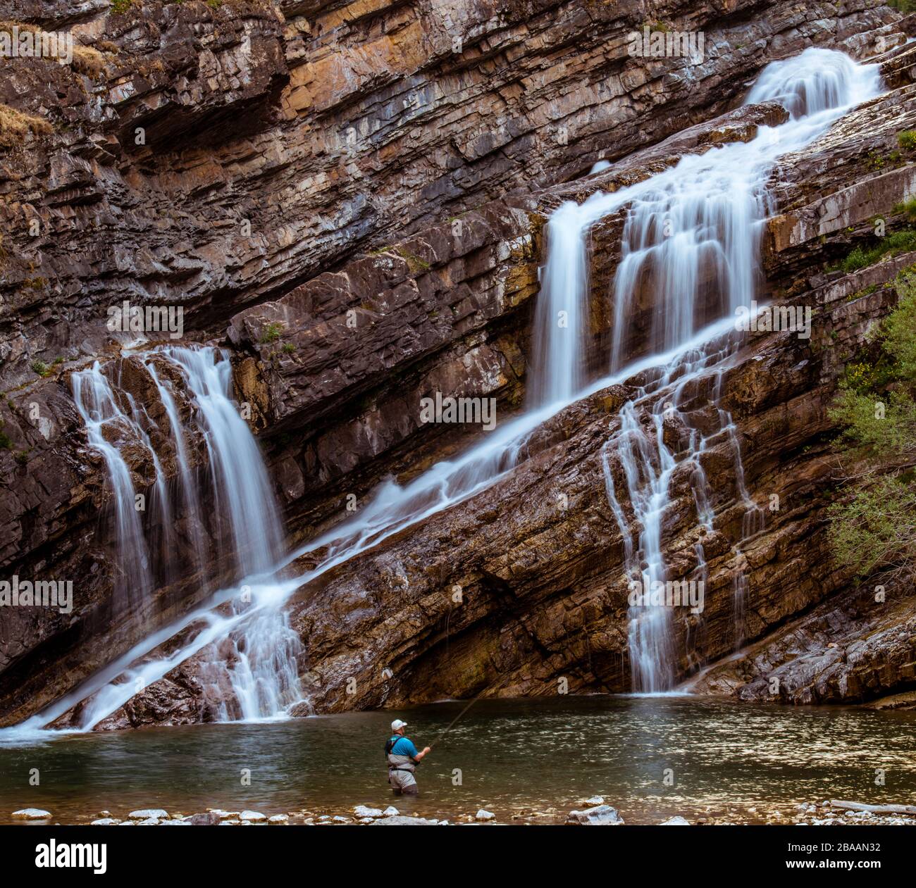 Man fishing at base of Cameron Falls, Waterton, Alberta, Canada Stock Photo