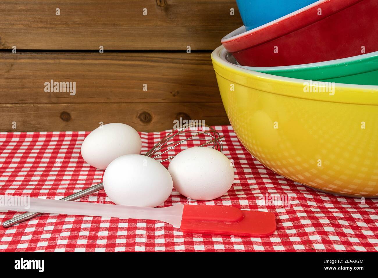 https://c8.alamy.com/comp/2BAAR2M/stack-of-retro-mixing-bowls-on-checkered-tablecloth-with-white-eggs-and-kitchen-utensils-2BAAR2M.jpg