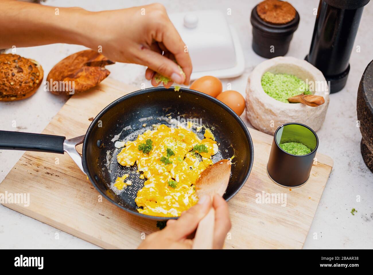 Scrambled eggs in a pan are seasoned with natural herb salt Stock Photo