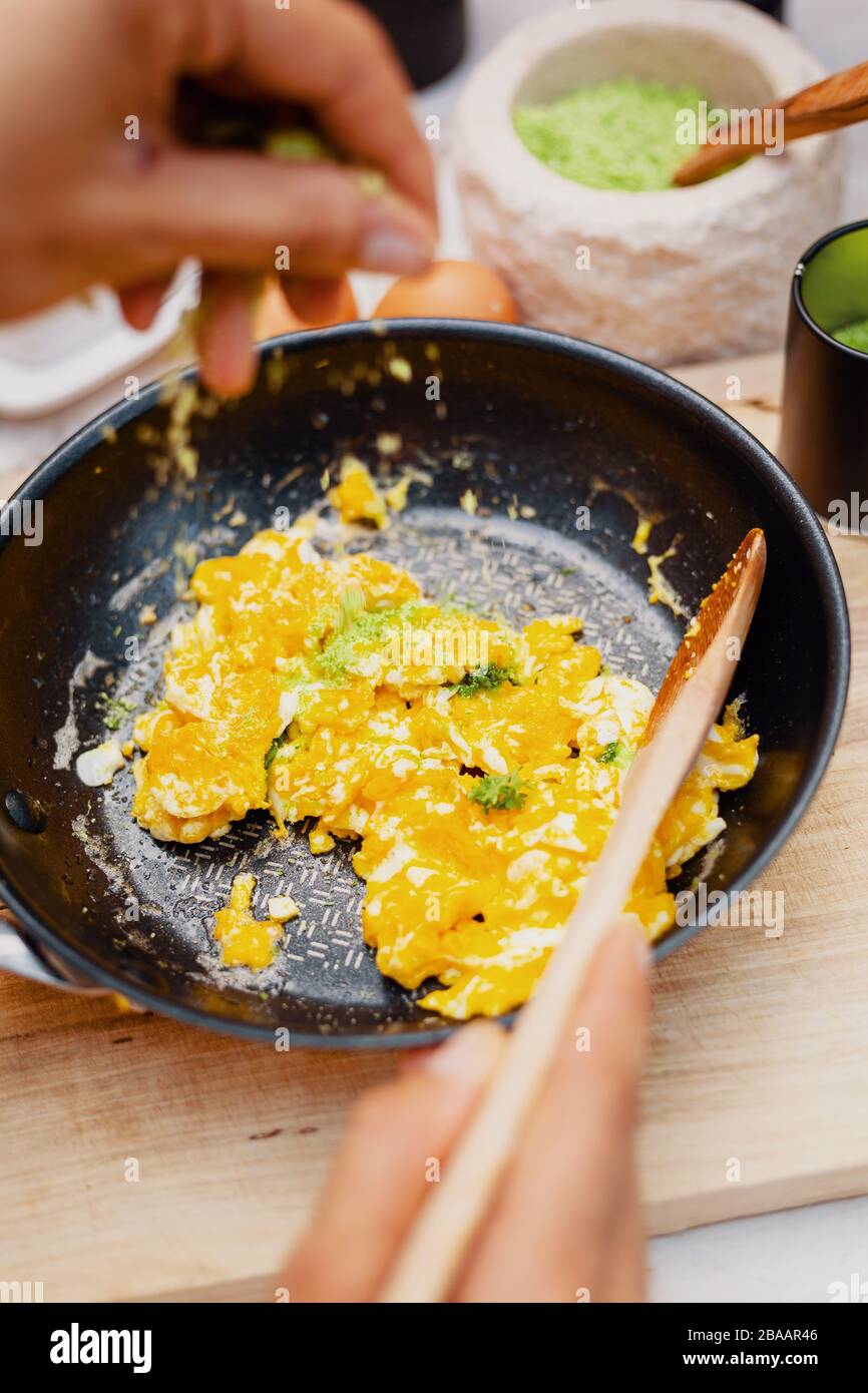 Scrambled eggs in a pan are seasoned with natural herb salt Stock Photo -  Alamy