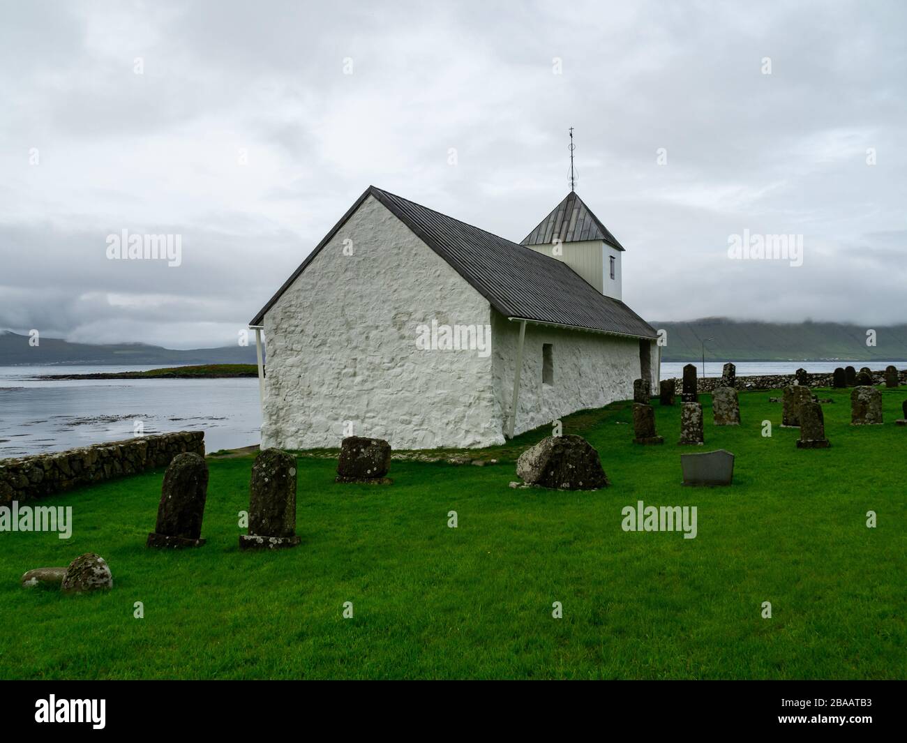 Faroe Islands. Saint Olav's Church in Kirkjubøur village. View for the old cemetery and back of the church. Stock Photo