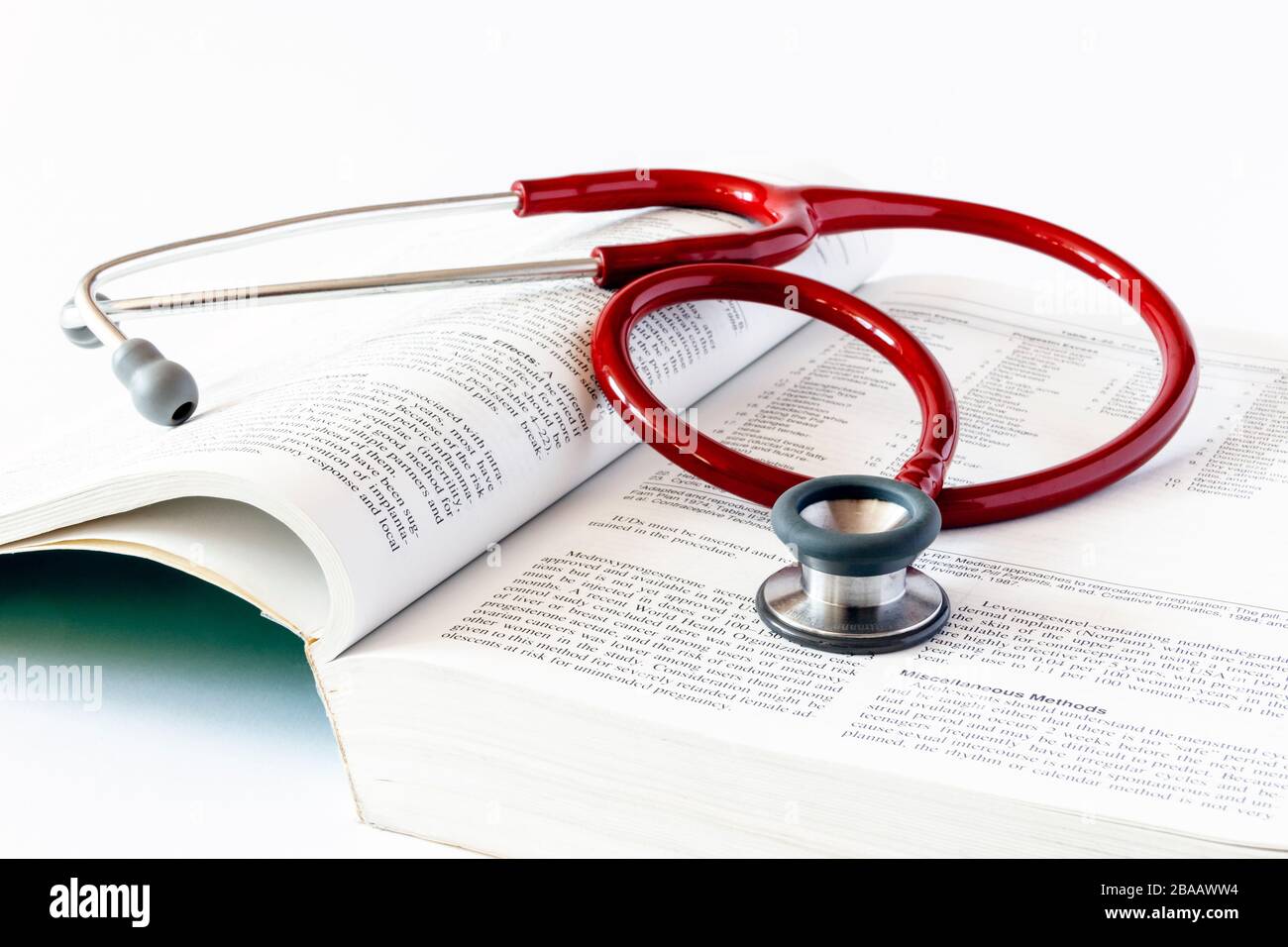A red stethoscope on an open medical textbook Stock Photo