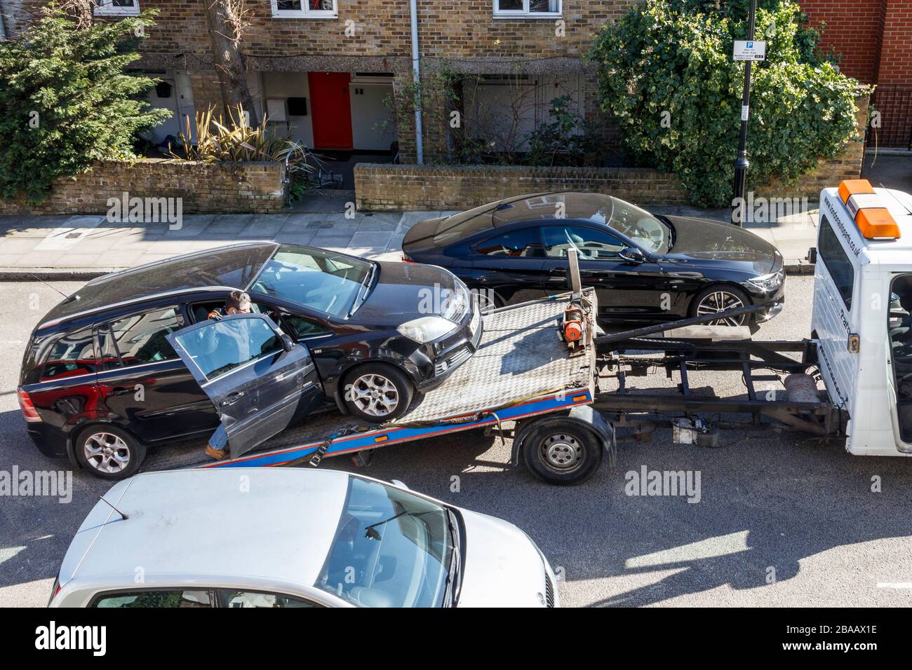 A car being winched onto the back of a recovery truck in a residential street in North London, UK Stock Photo