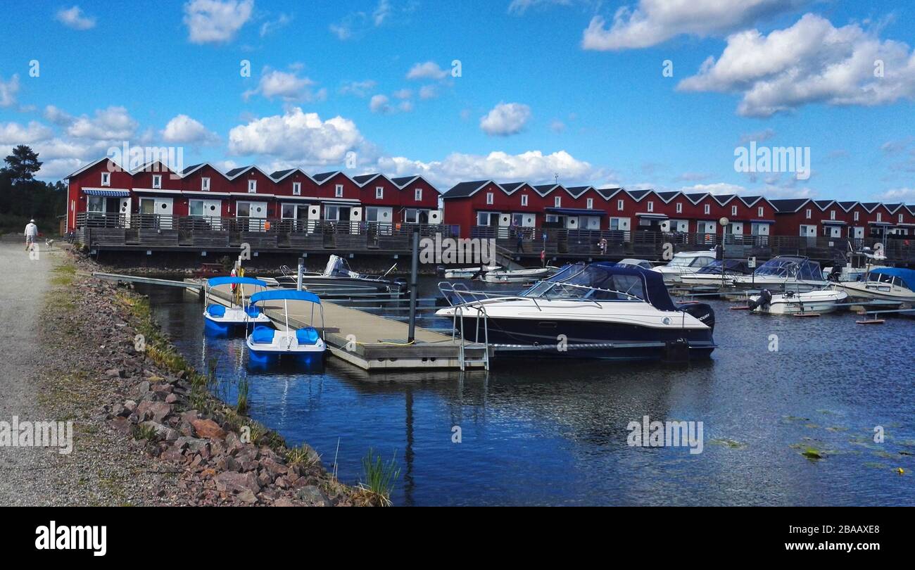 Tiny red Cabin or Shed Lined Up and Boats Moored at Marina in Sweden Stock Photo