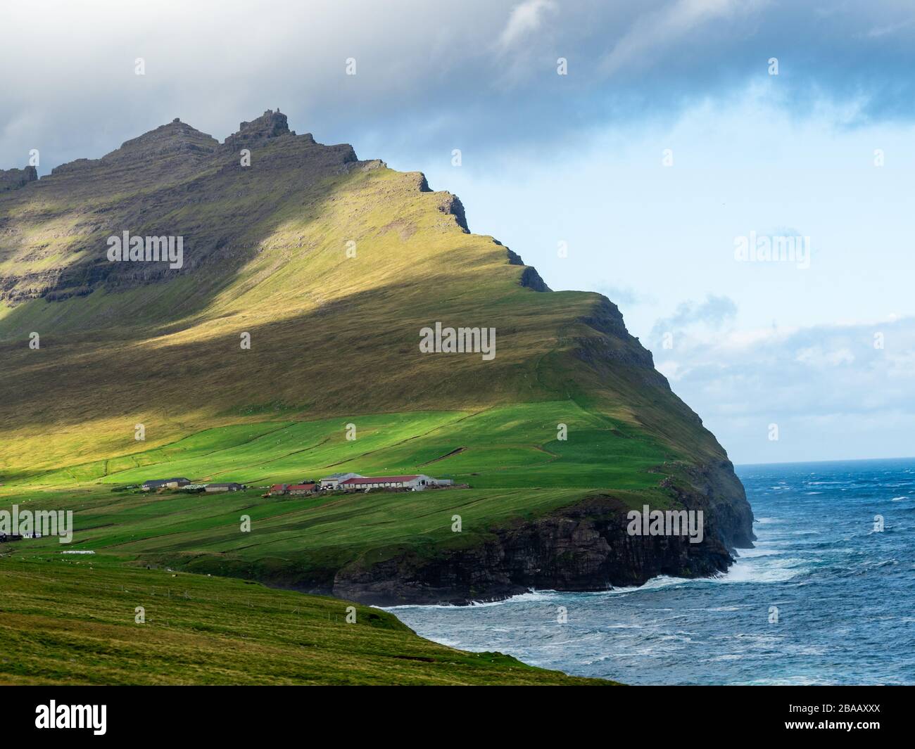 Faroe Islands, Viðoy, Viðareiði. Spectacular view on cliffs and green hills above the village. Blue sky with some while clouds. Stock Photo