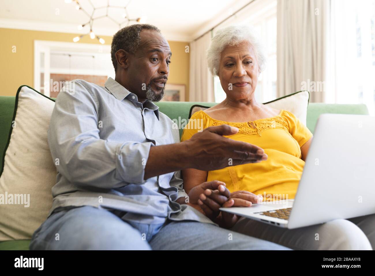 Senior African American couple using laptop in a canape Stock Photo