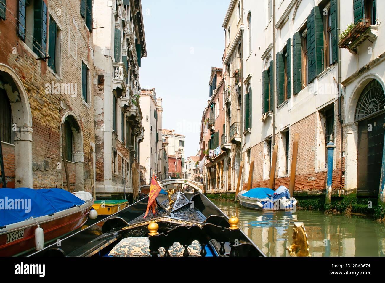View while riding in a gondola. Approaching an arched bridge with buildings on both sides of the canal. Venice, Italy. Stock Photo
