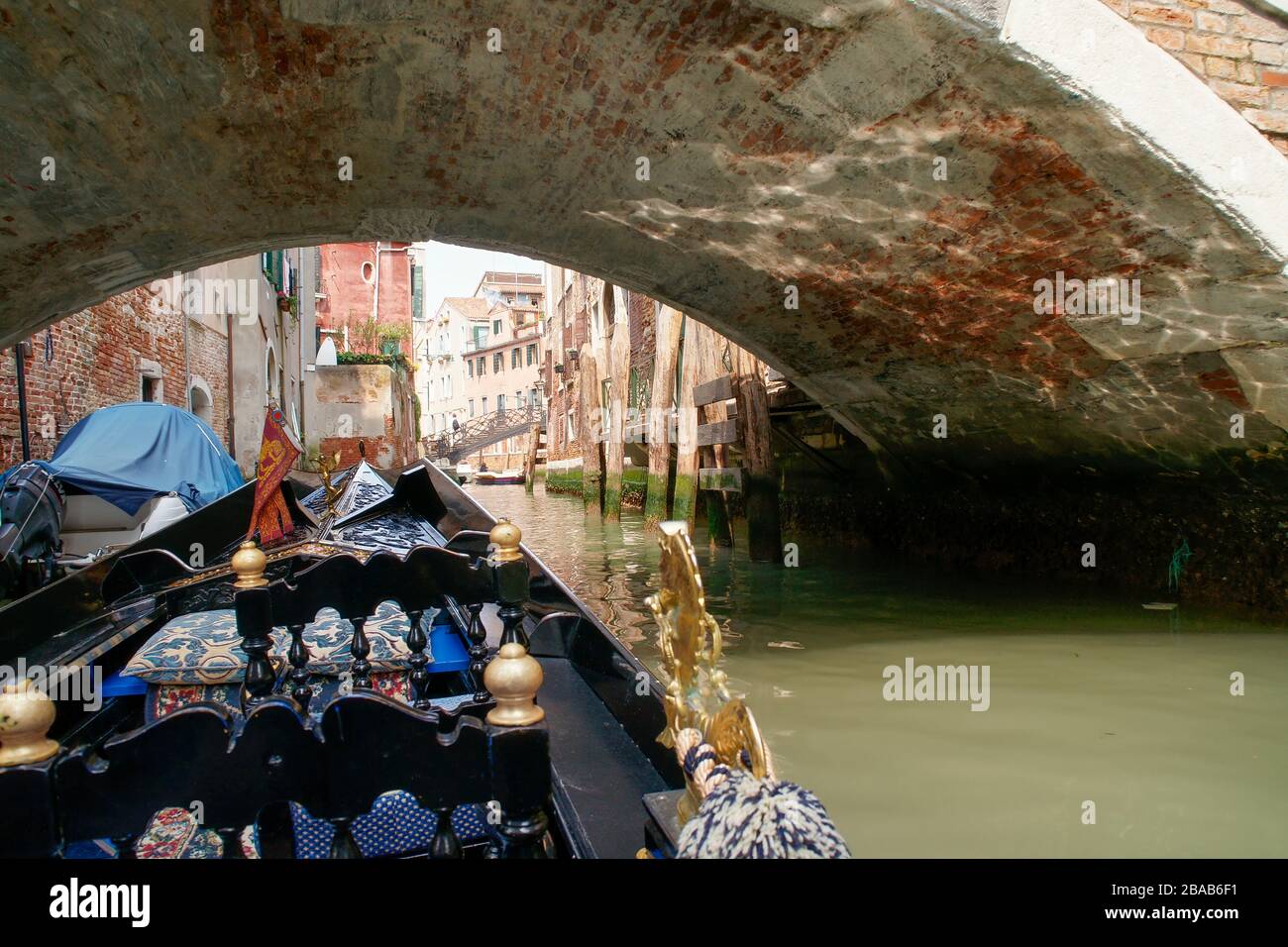 View while riding in a gondola. Passing under one of the traditional arched bridges with buildings on both sides of the canal. Venice, Italy. Stock Photo