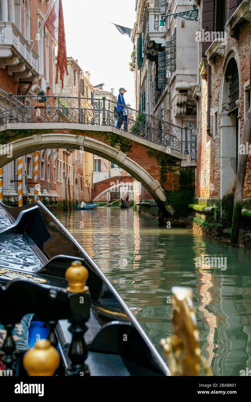 Classic view while riding in a gondola. A bridge with people crossing, buildings on both sides and an approaching gondola in the background. NMR Stock Photo