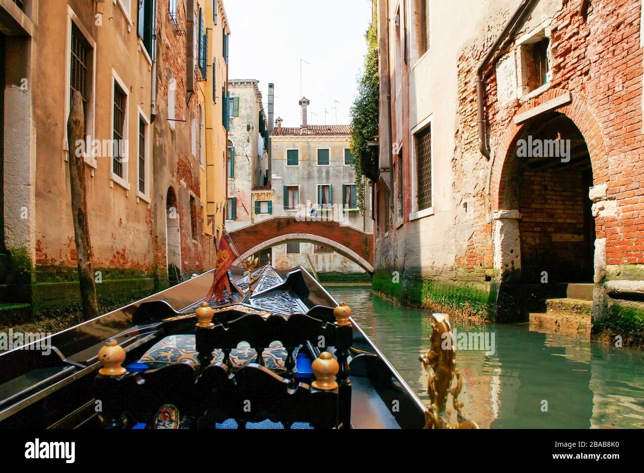 View while riding in a gondola. Approaching one of the traditional arched bridges with buildings on both sides of the canal. Venice, Italy. Stock Photo