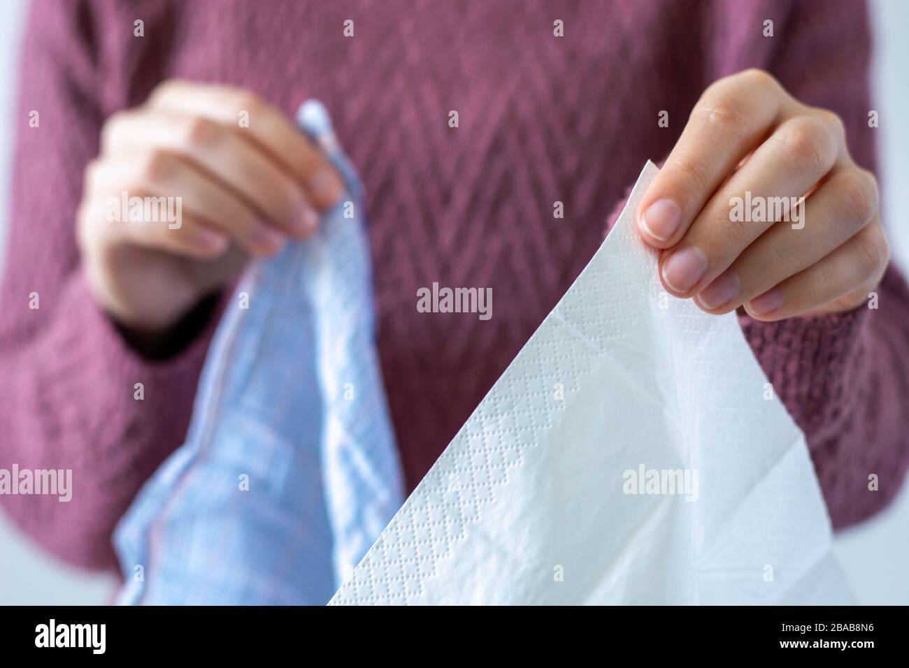 A woman is holding a paper tissue and a cotton handkerchief. Coronavirus advice includes use a disposable paper tissue instead of a cotton one Stock Photo