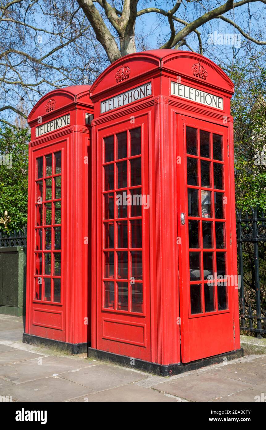 Pair of old-fashioned red British phone boxes standing on a spring sidewalk in London, UK Stock Photo