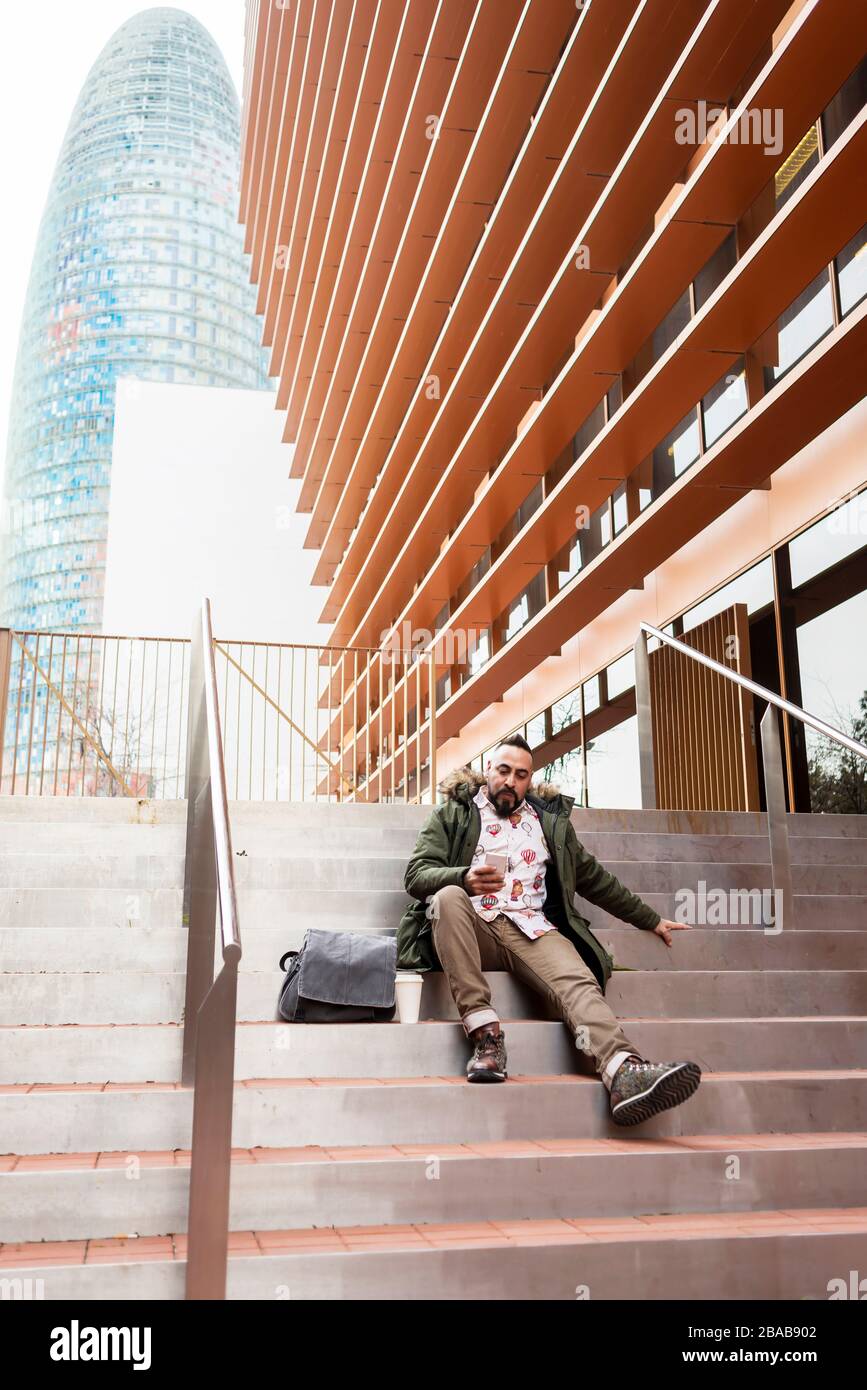 Handsome young man dressed casually spending time outdoors with mobile Stock Photo