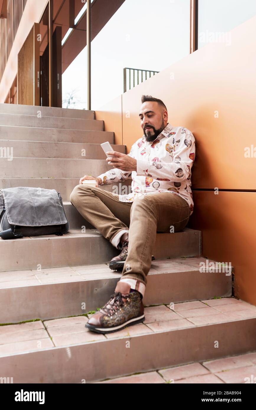 Handsome young man dressed casually spending time outdoors with mobile Stock Photo