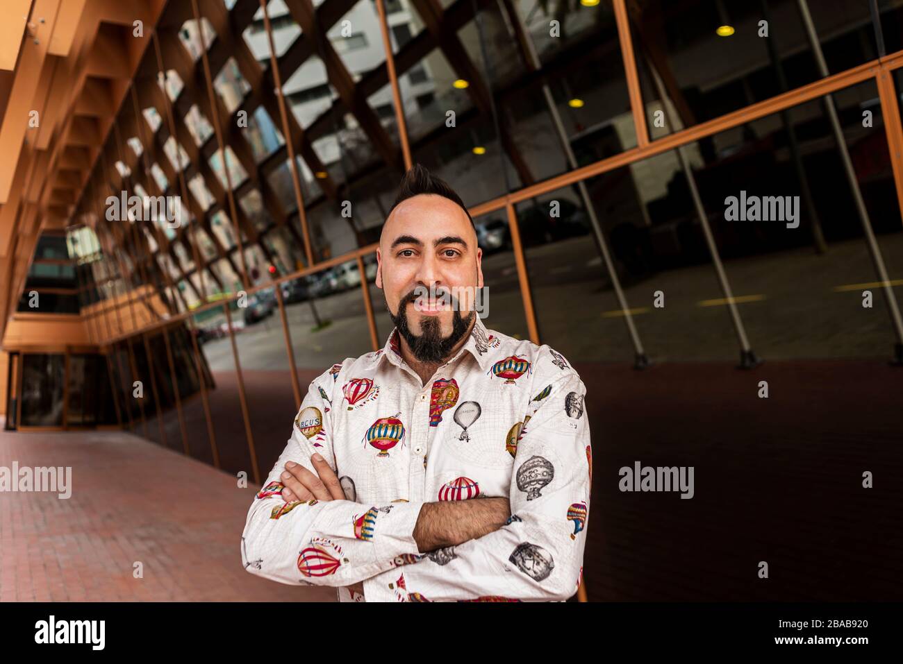 Bearded man with crossed arms while standing against office building. Stock Photo