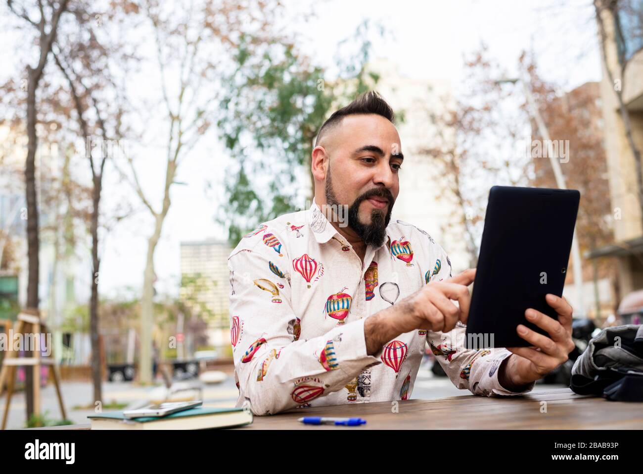 Young bearded businessman sitting at table,using tablet computer Stock Photo