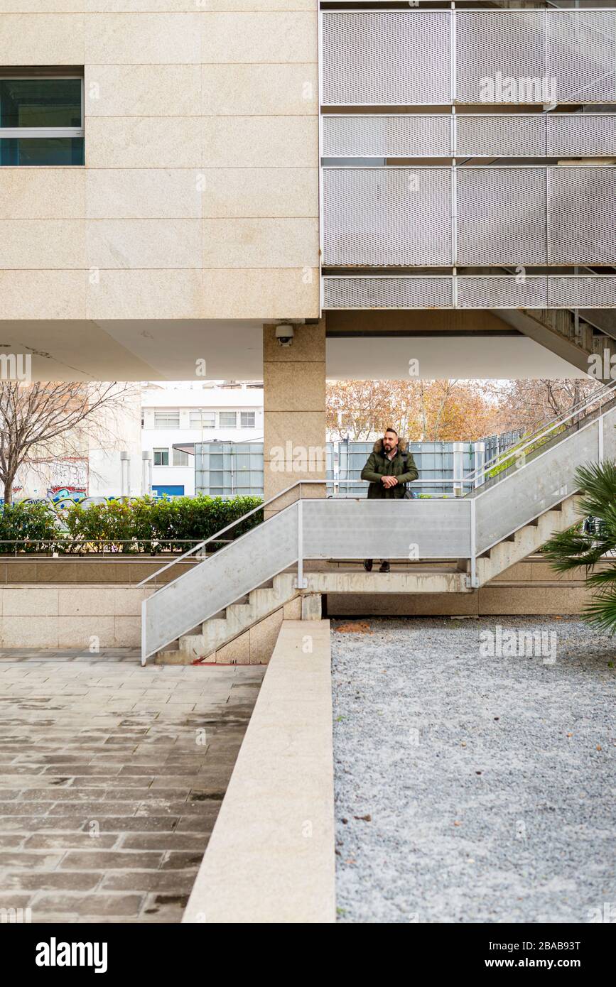 Bearded hipster man relaxing on stairs in a building complex Stock Photo