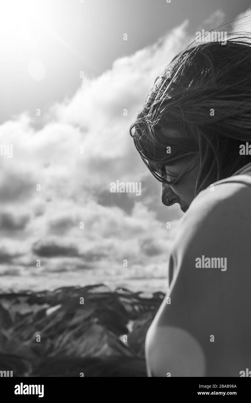 Side view of meditative young woman sitting on top of mountain Stock Photo