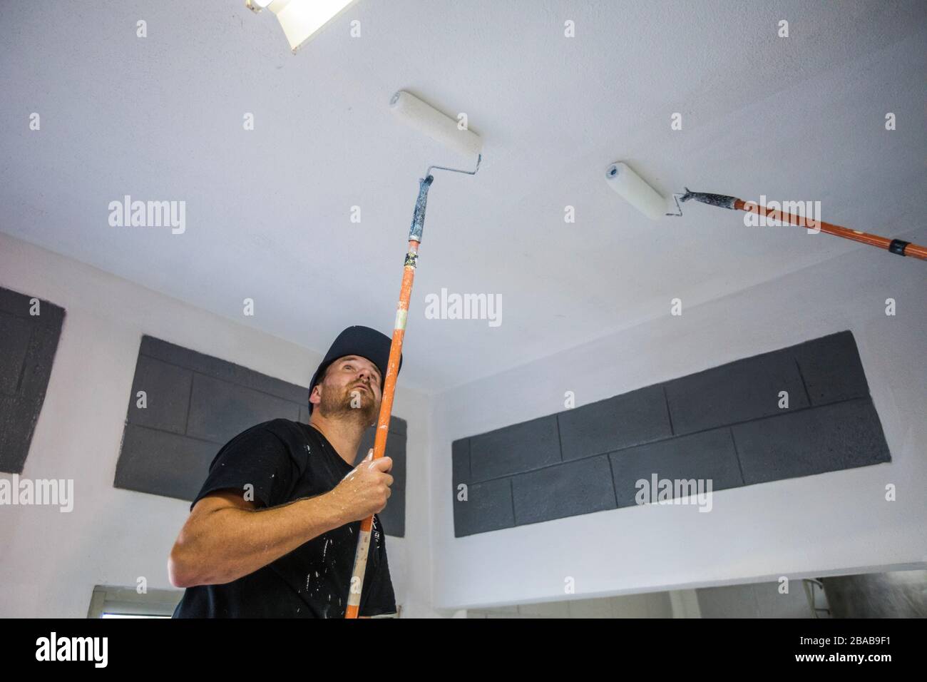Painter uses roller to paint ceiling white Stock Photo Alamy