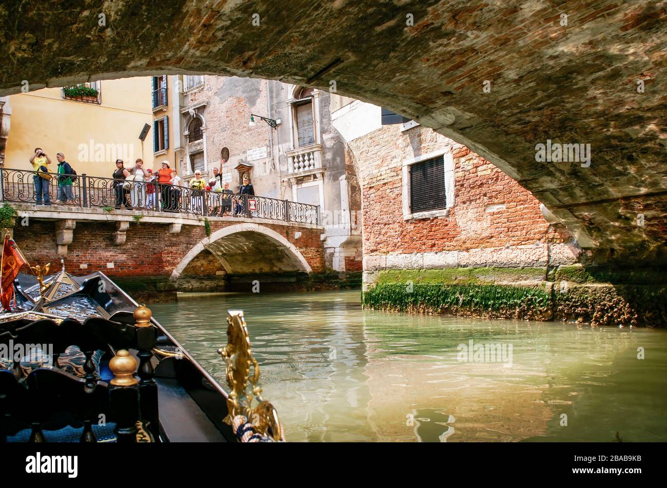 Tourists waving and taking photos as we ride in a gondola. Venice, Italy. NMR Stock Photo