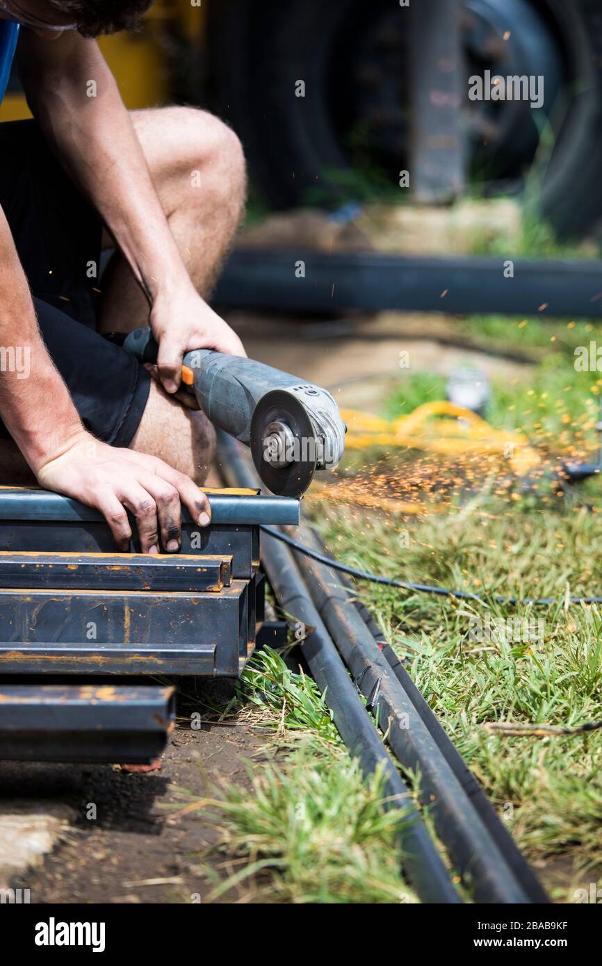 Worker uses angle grinder to cut steel on construction site Stock Photo
