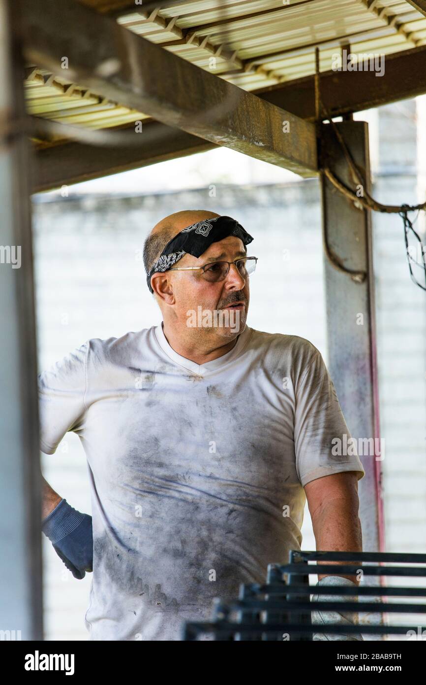 Portrait of a metal worker standing in workshop with dirty shirt. Stock Photo