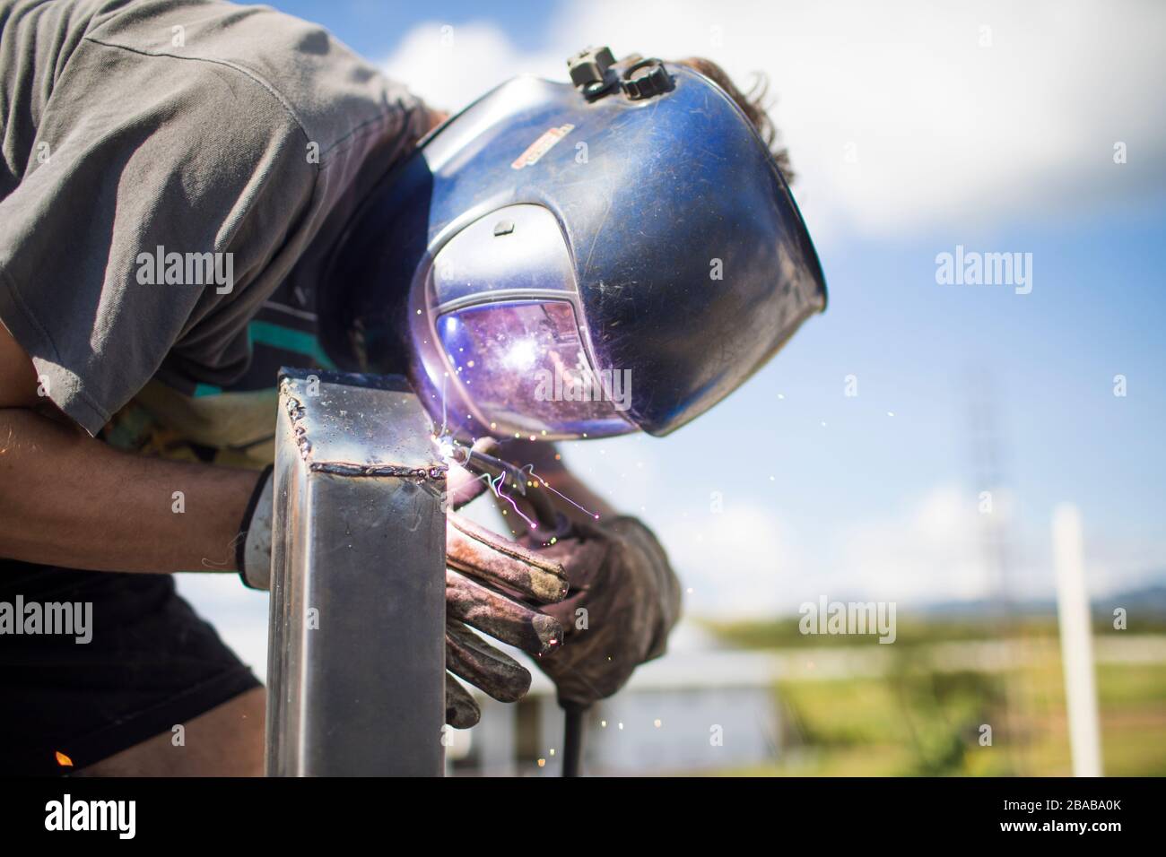 close up view of man welding outdoors on rooftop. Stock Photo