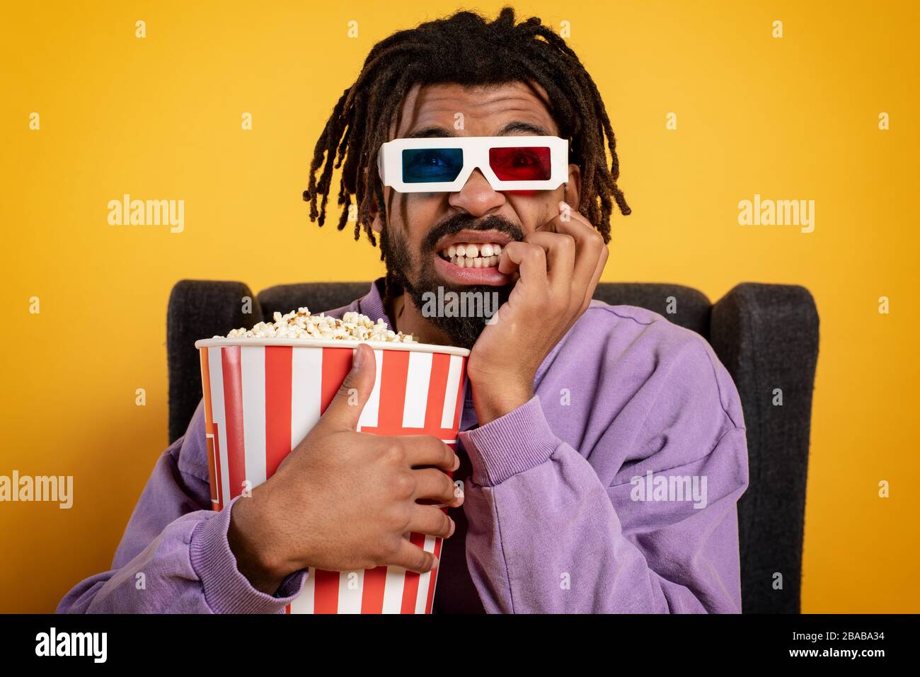Boy has fun watching a film. Concept of entertainment and streaming tv. yellow background Stock Photo
