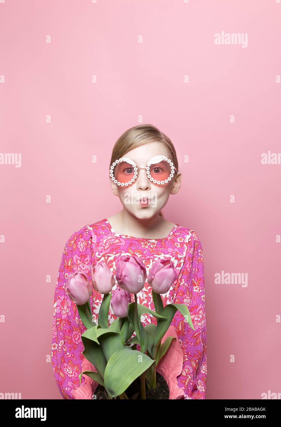 Mod blonde tween girl, blue eyes, pink background, pink floral dress Stock Photo