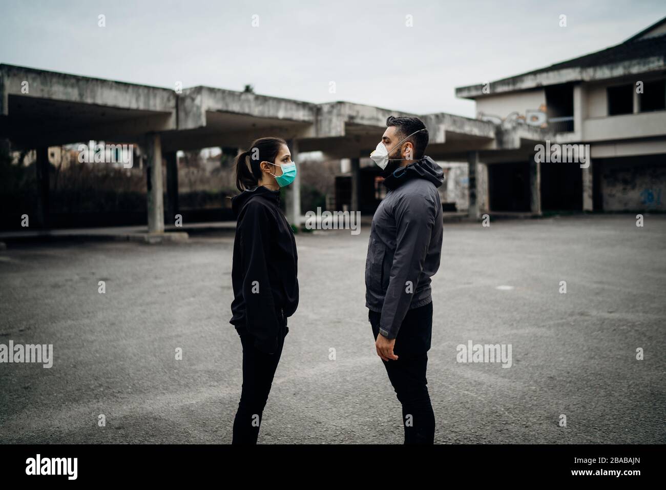 Two people in masks talking from distance.Couple being divided by incurable infectious disease.Infection control,isolation.Loved one illness.Saying go Stock Photo