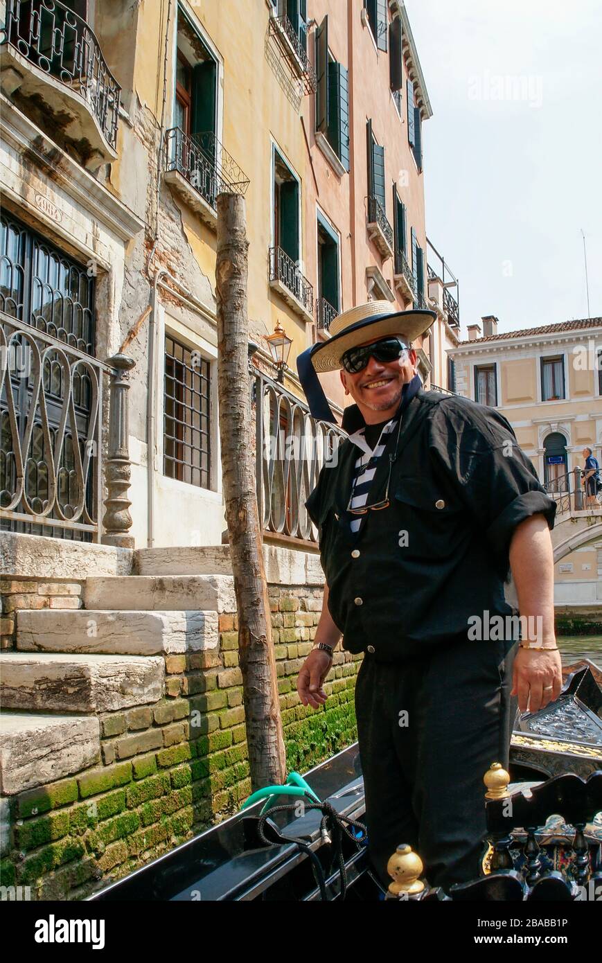 Happy, smiling gondolier standing in his boat as he waits to board passengers. Venice, Italy. NMR Stock Photo