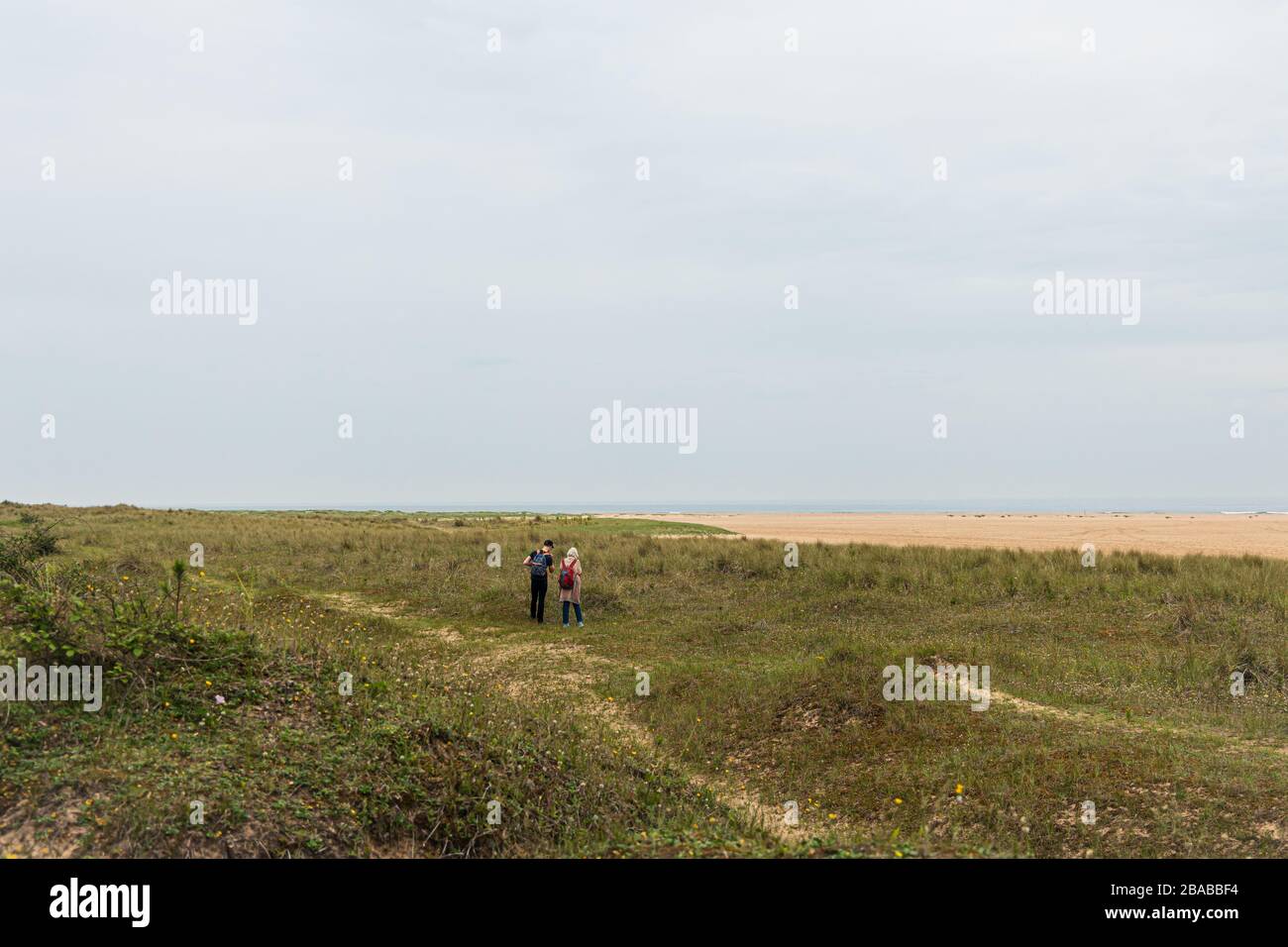 2 People Walking along the Norfolk Coast Stock Photo