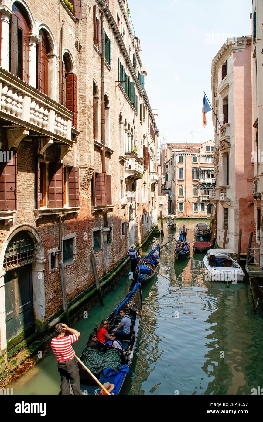 Several gondolas with tourists passing in a side canal. Venice, Italy. NMR Stock Photo