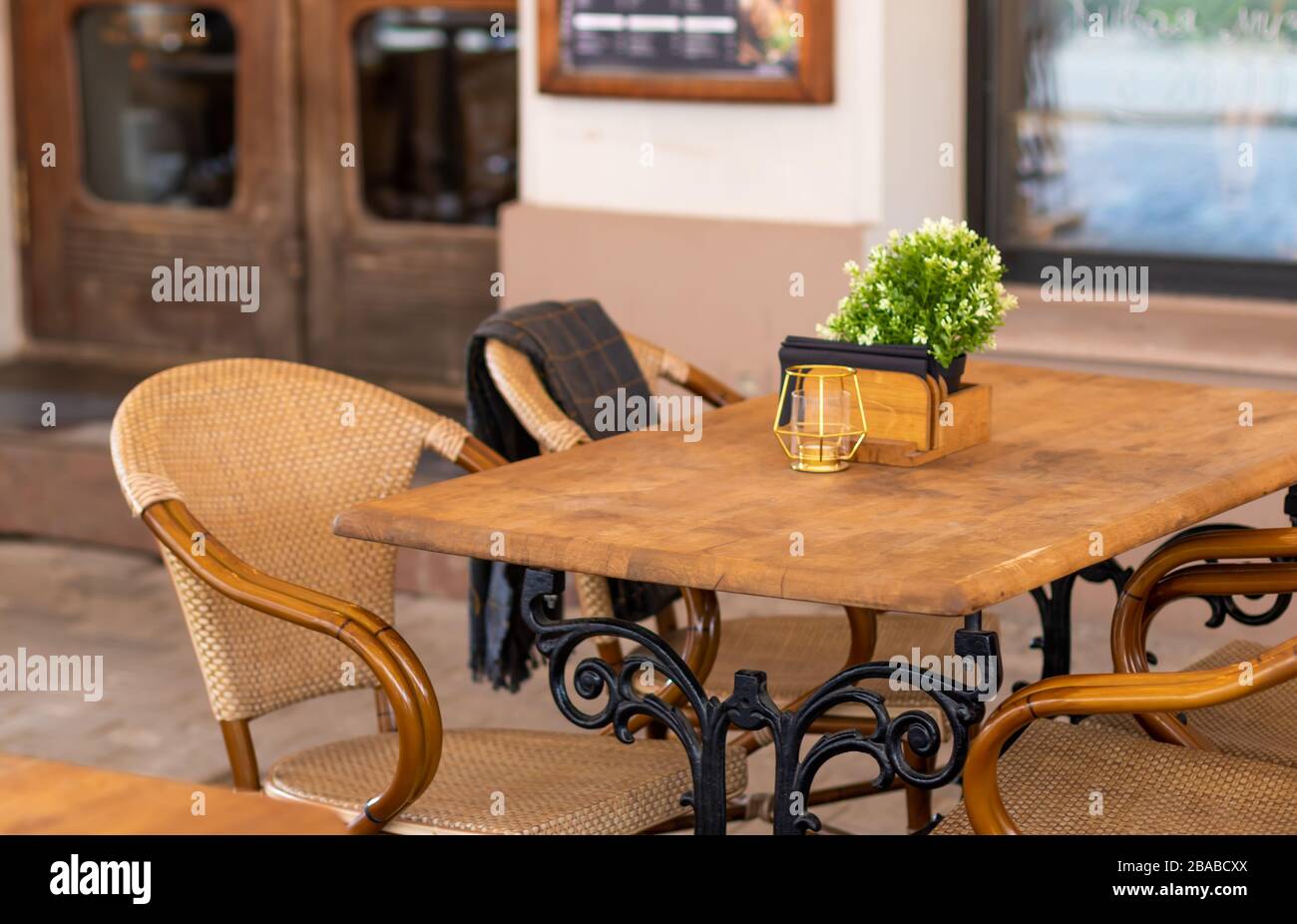 Wooden table with napkins and condiments at completely empty rustic restaurant with now people and customers during covid 19 corona virus pandemic shu Stock Photo