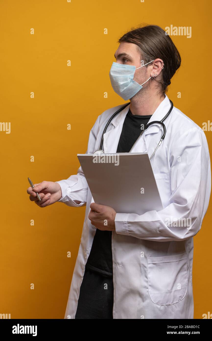 Young doctor with stethoscope, holding a map and a pen is explaining something to someone visible not in the frame due to a minimum 1.5m distance requ Stock Photo