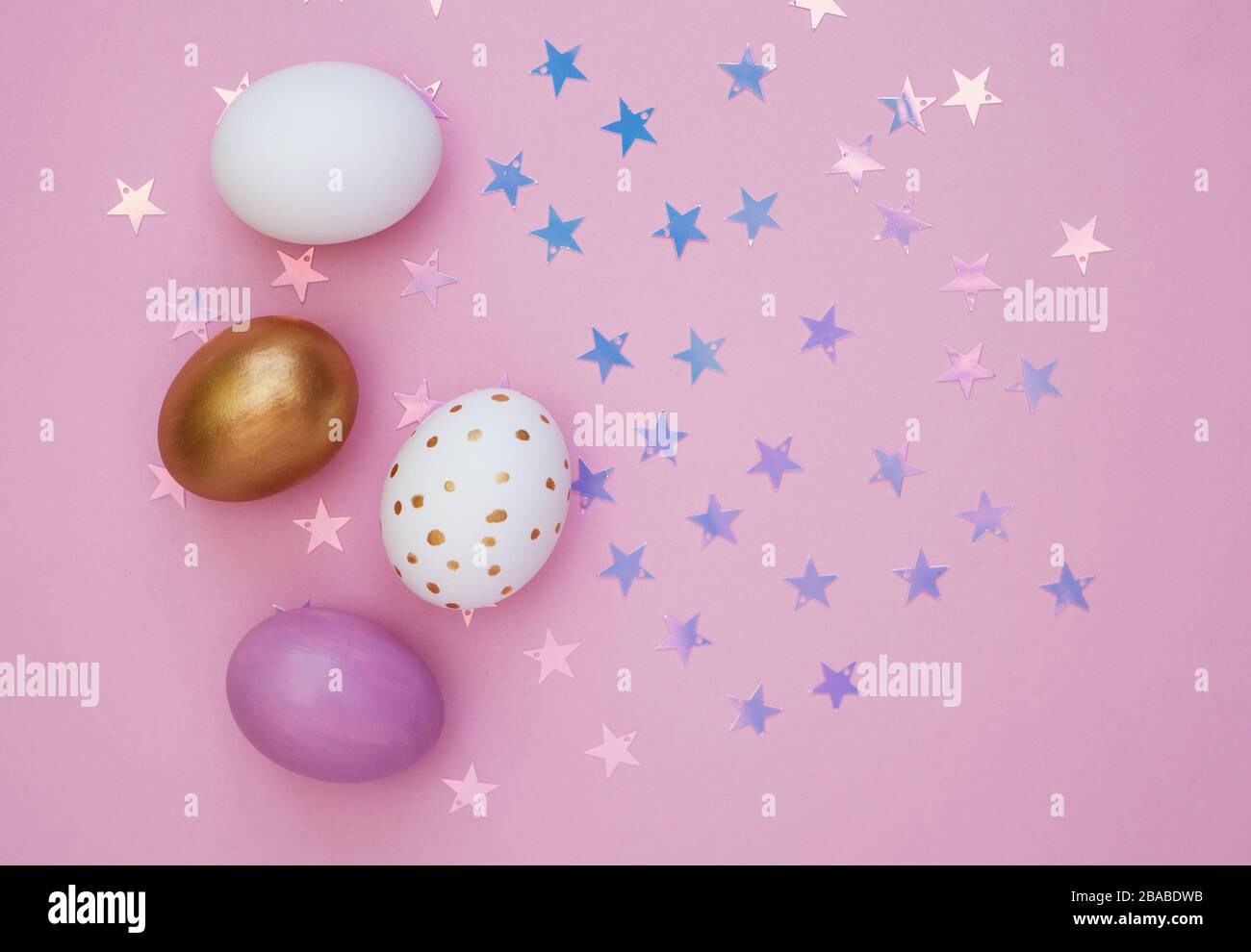 Colorful Easter eggs over pink background. Star shiny confetti Stock Photo