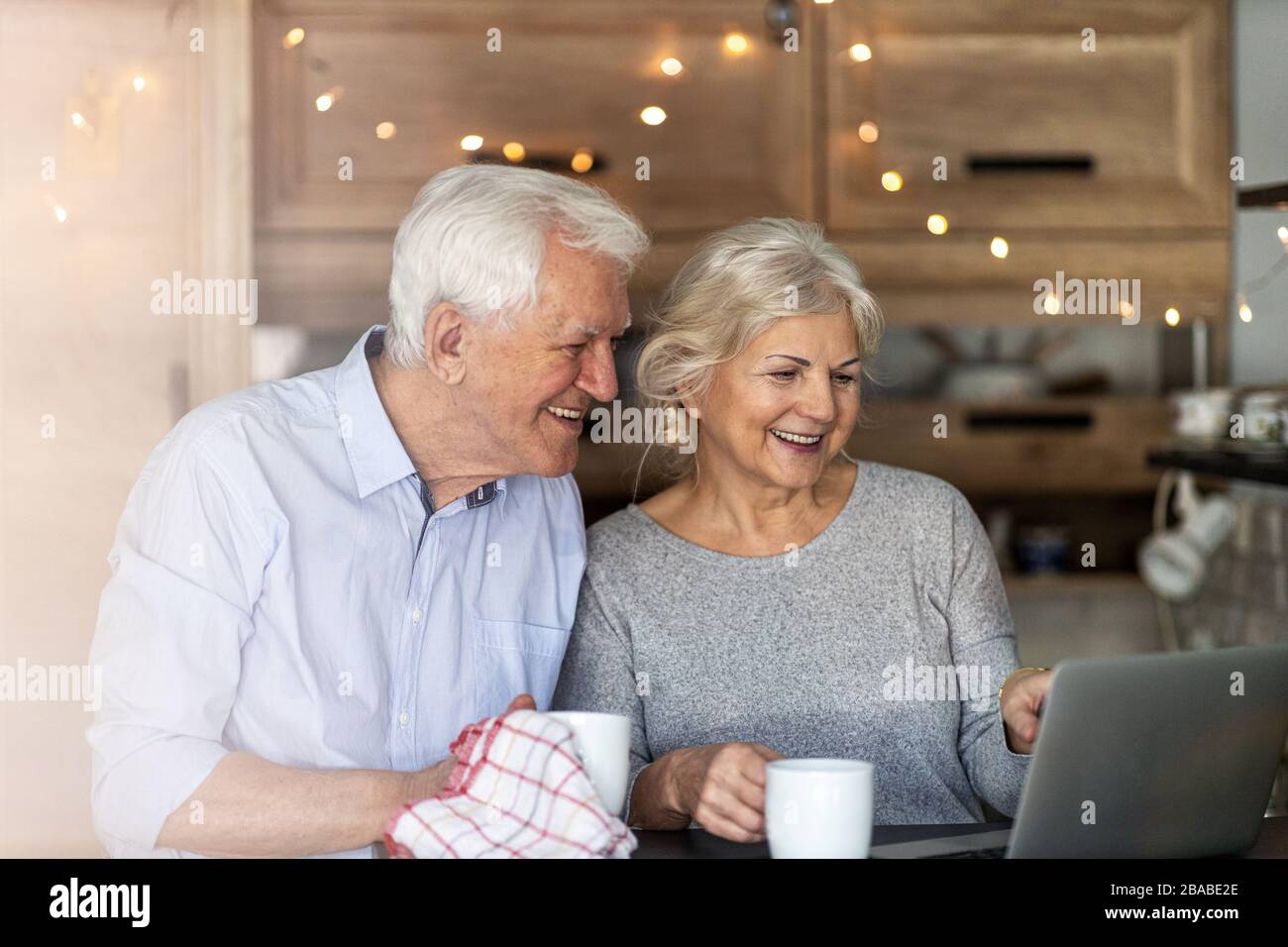 Senior couple using laptop in their kitchen Stock Photo
