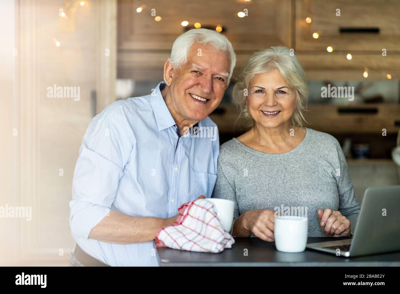Senior couple using laptop in their kitchen Stock Photo